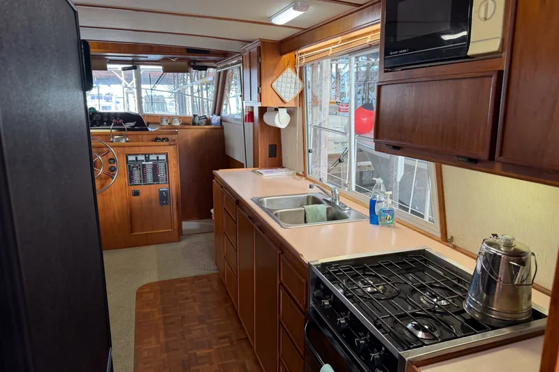Slide: The Image of Interior of a 1990 Cruise-A-Home Corsair boat featuring a kitchen with stove and sink. - 43