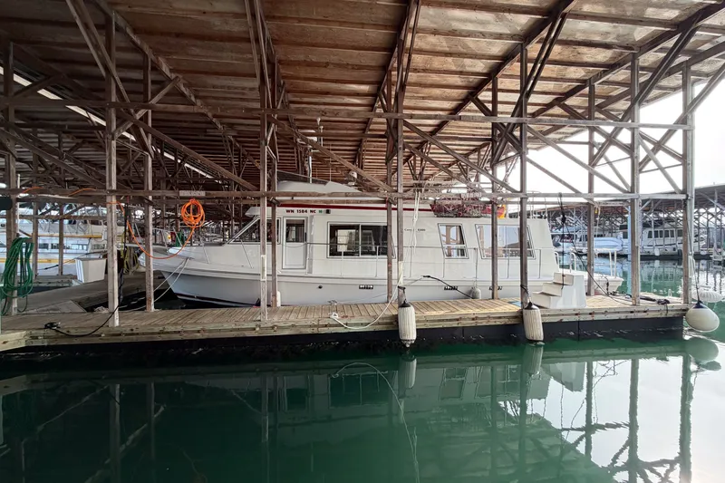 Slide: The Image of 1990 Cruise-A-Home Corsair docked under a wooden marina shelter. - 77