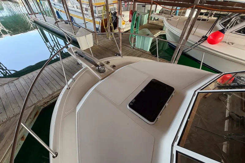 Slide: The Image of 1990 Cruise-A-Home Corsair boat docked in a marina, featuring deck and railing. - 72
