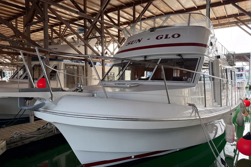 Slide: The Image of 1990 Cruise-A-Home Corsair boat docked in a marina under a wooden shelter. - 75
