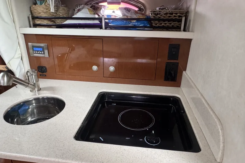 Slide: The Image of Compact kitchen area in a 2008 Sea Ray 290 Sundancer boat with sink and stove. - 16
