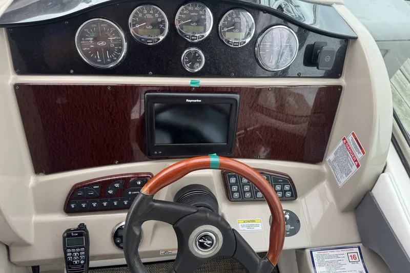Slide: The Image of 2008 Sea Ray 290 Sundancer dashboard with gauges, Raymarine display, and wood-accented steering wheel. - 5
