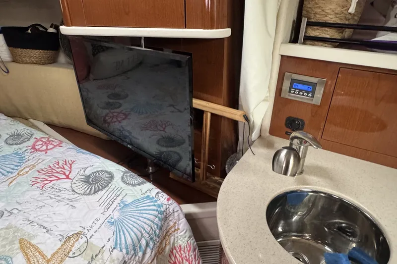 Slide: The Image of Interior of 2008 Sea Ray 290 Sundancer with TV, sink, and nautical-themed bedding. - 15