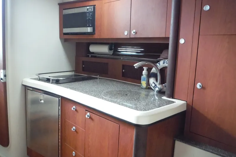 Slide: The Image of 2007 Monterey 330 Sport Yacht kitchen with wood cabinets, microwave, and stainless steel appliances. - 23