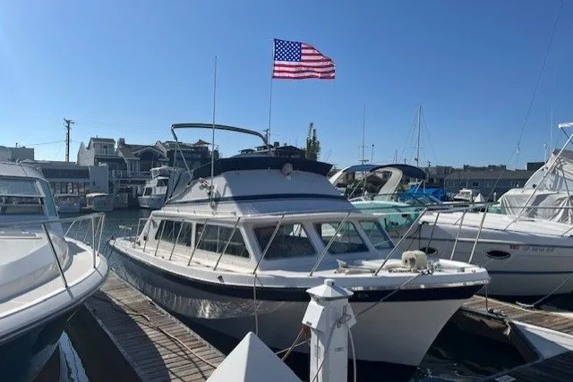 The Image of 1972 Luhrs 32 Convertible boat docked, American flag waving, clear blue sky. - 0