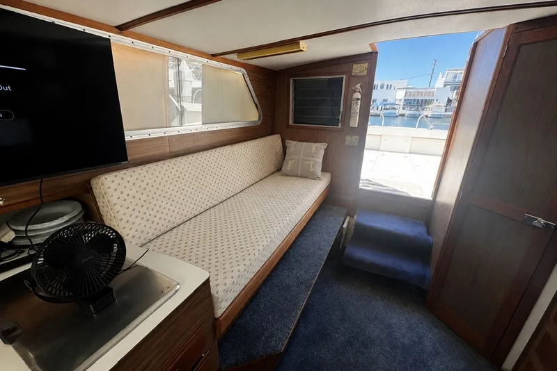 Slide: The Image of Interior of a 1972 Luhrs 32 Convertible boat with sofa, TV, and marina view. - 9