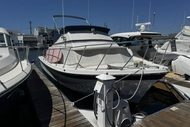 Slide: The Image of 1972 Luhrs 32 Convertible boat docked at marina under clear blue sky. - 2