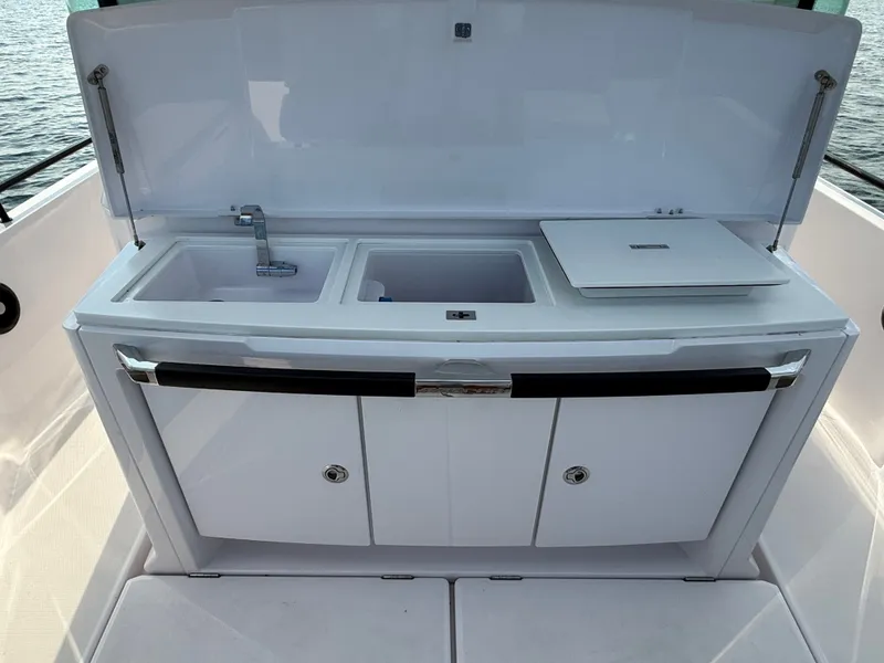 Slide: The Image of The 2023 Axopar Brabus 37 XC Cross Cabin features a sleek outdoor kitchen with a sink and storage. - 11