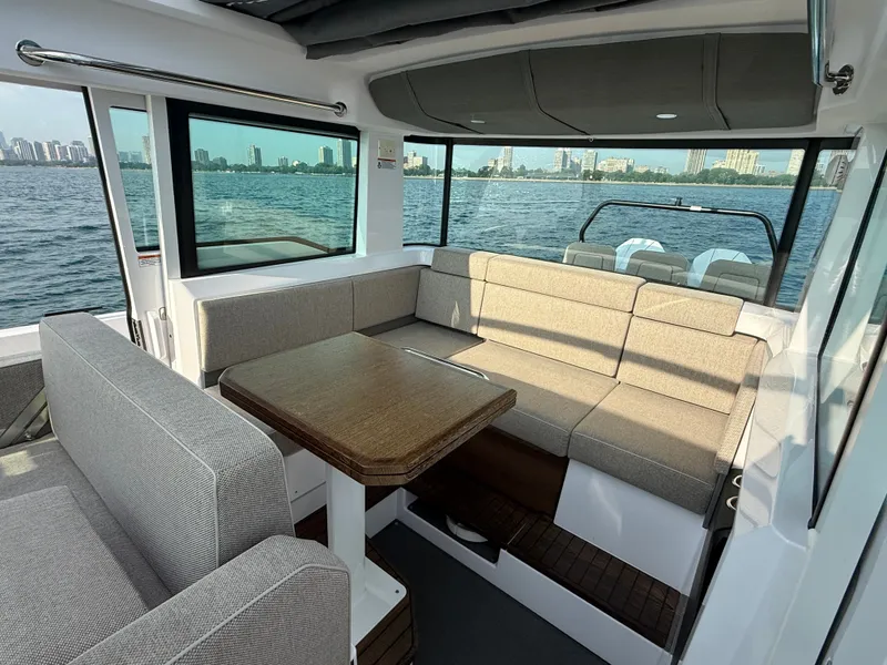 Slide: The Image of Interior of the Axopar Brabus 37 XC Cross Cabin with gray upholstery and wooden table, overlooking water. - 22