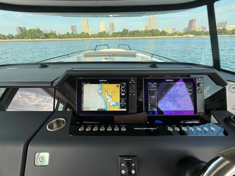 Slide: The Image of The cockpit of the Axopar Brabus 37 XC Cross Cabin features modern navigation systems with a cityscape in the background. - 25