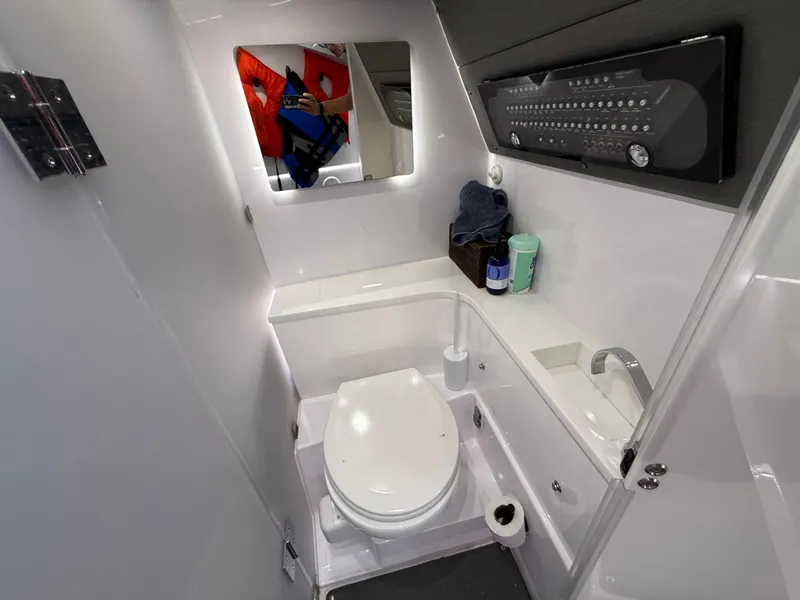 Slide: The Image of The image shows a modern boat bathroom with a toilet, sink, and mirror. - 33
