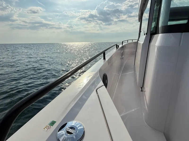 Slide: The Image of The 2023 Axopar Brabus 37 XC Cross Cabin glides over calm waters at sunset. - 12