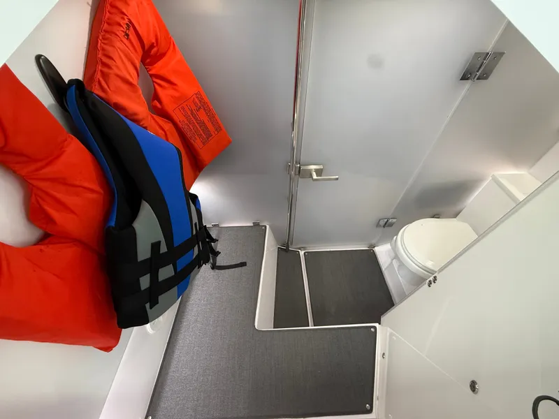 Slide: The Image of Interior of a boat cabin with a toilet, gray flooring, and life jackets on the wall. - 32