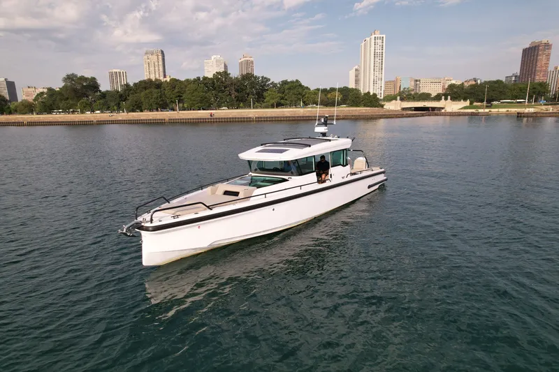 Slide: The Image of A 2023 Axopar Brabus 37 XC Cross Cabin on calm water with a city skyline in the background. - 2