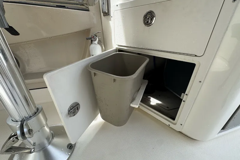Slide: The Image of Boston Whaler 320 Vantage 2021 boat interior with open storage compartment and trash bin. - 53