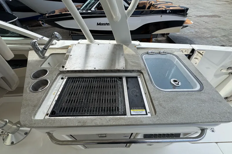 Slide: The Image of Boston Whaler 320 Vantage 2021 boat kitchen with grill, sink, and cup holders. - 49