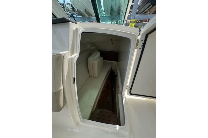 Slide: The Image of 2021 Boston Whaler 320 Vantage cabin interior with open door, showcasing seating and storage. - 68