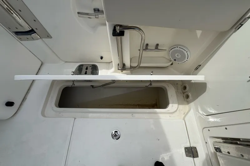 Slide: The Image of 2021 Boston Whaler 320 Vantage storage compartment with open hatch and visible speaker. - 43