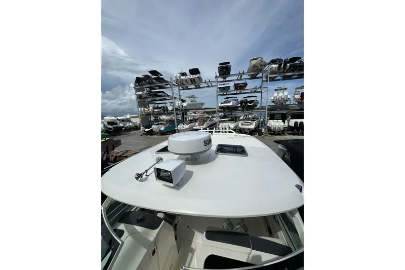 Slide: The Image of 2021 Boston Whaler 320 Vantage boat in storage yard with stacked vessels. - 87