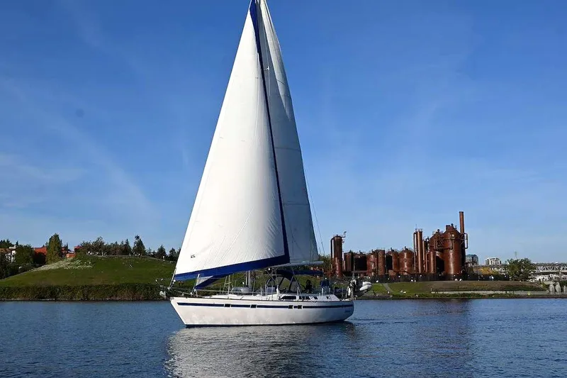 The Image of Sailing yacht Taswell 43, 1989 model, cruising near industrial structures on a sunny day. - 1