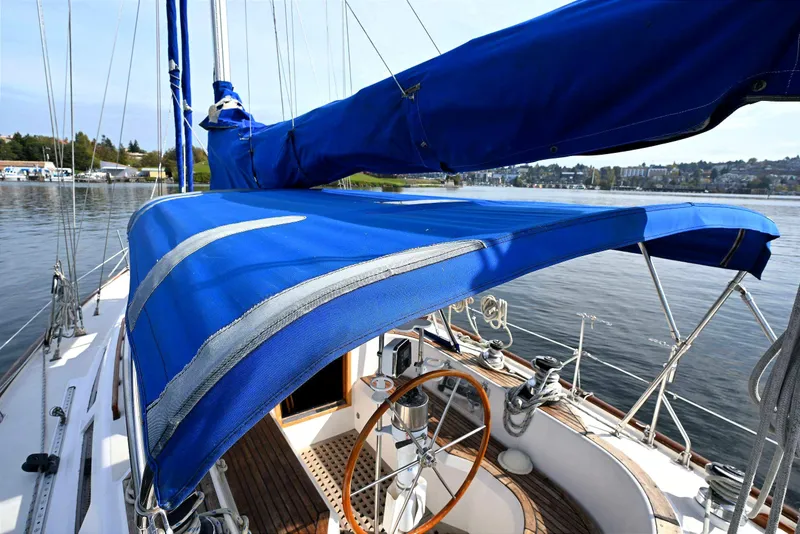 Slide: The Image of 1989 Ta Shing Yachts Taswell 43 sailboat with blue canvas cover on calm water. - 10