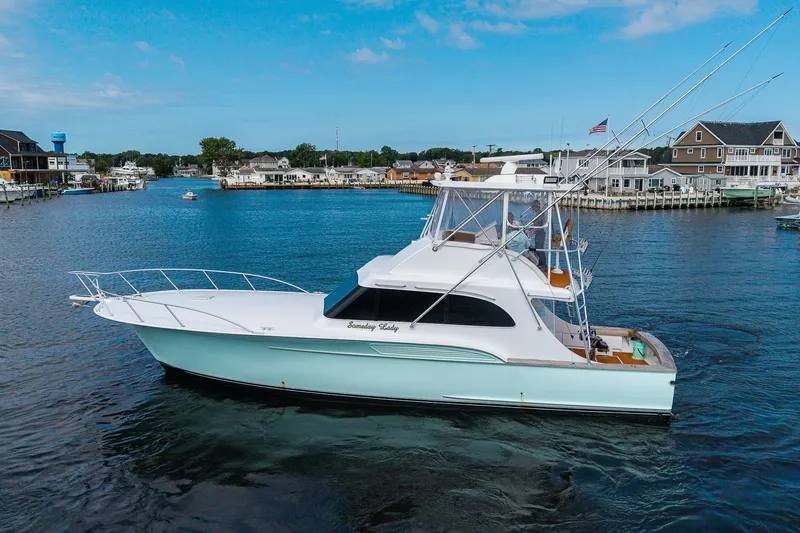 Slide: The Image of 1986 Buddy Davis 47 Convertible yacht cruising in a scenic harbor. - 56