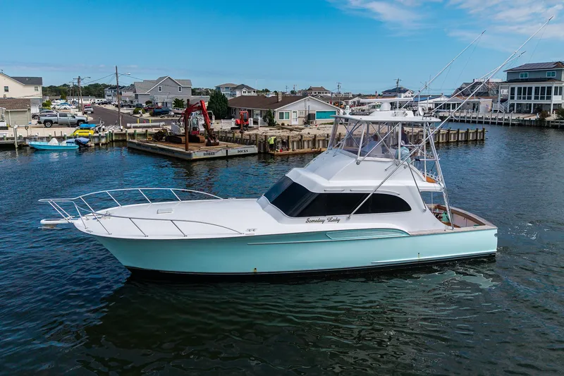 Slide: The Image of 1986 Buddy Davis 47 Convertible yacht docked in a scenic marina setting. - 46