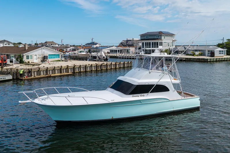 Slide: The Image of 1986 Buddy Davis 47 Convertible yacht docked in a scenic waterfront setting. - 45