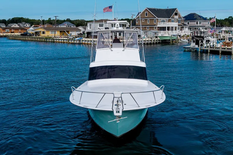 Slide: The Image of 1986 Buddy Davis 47 Convertible yacht docked in a scenic marina setting. - 54