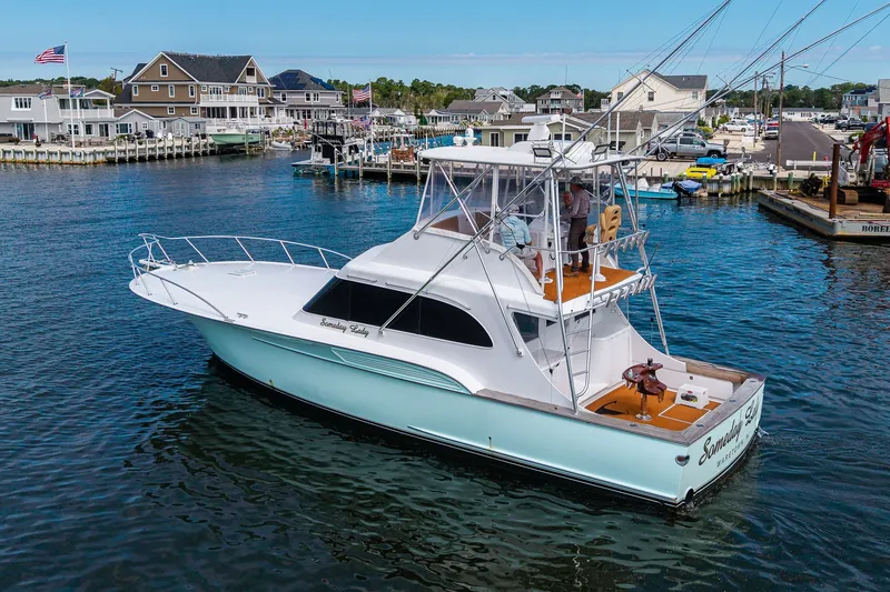 Slide: The Image of 1986 Buddy Davis 47 Convertible yacht docked in a scenic marina setting. - 48