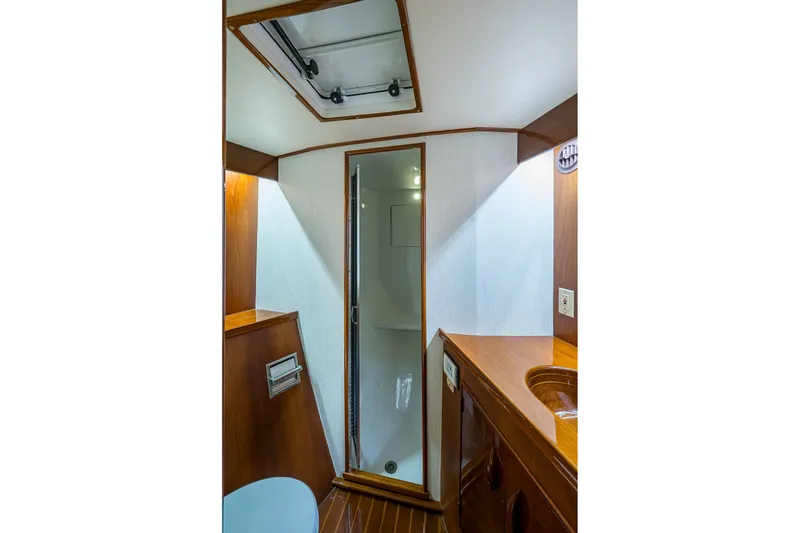 Slide: The Image of Interior of 1986 Buddy Davis 47 Convertible yacht, featuring a compact bathroom with wooden accents. - 32