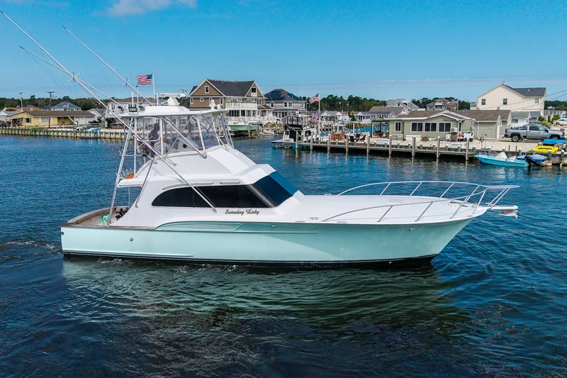 Slide: The Image of 1986 Buddy Davis 47 Convertible yacht cruising near a marina with waterfront homes. - 52