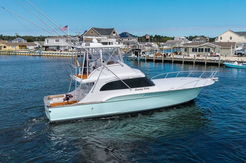 Slide: The Image of 1986 Buddy Davis 47 Convertible yacht cruising near a coastal marina. - 51