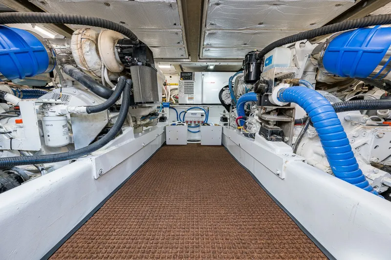 Slide: The Image of Engine room of 1986 Buddy Davis 47 Convertible yacht, featuring dual engines and blue hoses. - 15