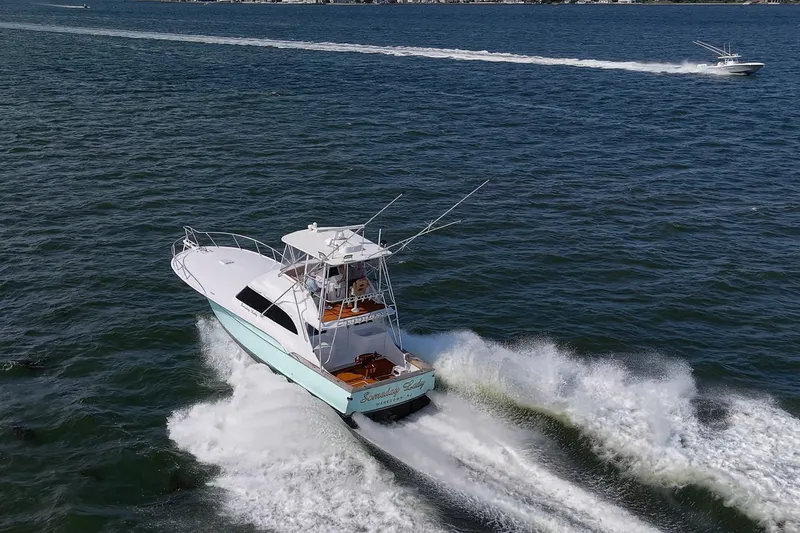 Slide: The Image of 1986 Buddy Davis 47 Convertible yacht cruising on open water, creating a dynamic wake. - 64