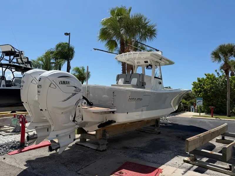 The Image of A 2022 Regulator 31 boat with twin Yamaha outboard engines, on a dock under palm trees. - 0