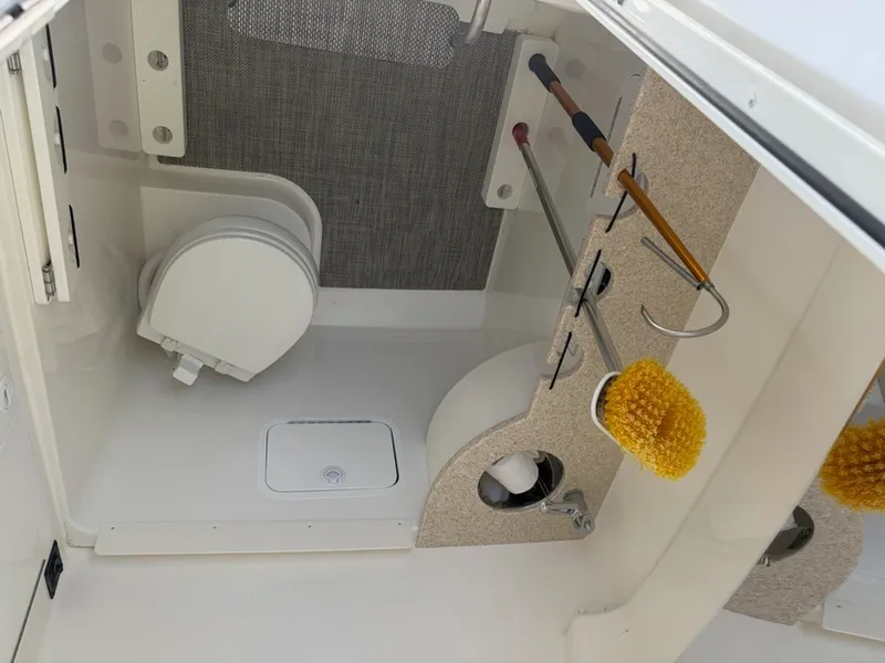 Slide: The Image of Interior of a boat with a toilet, cleaning brushes, and storage space. - 20