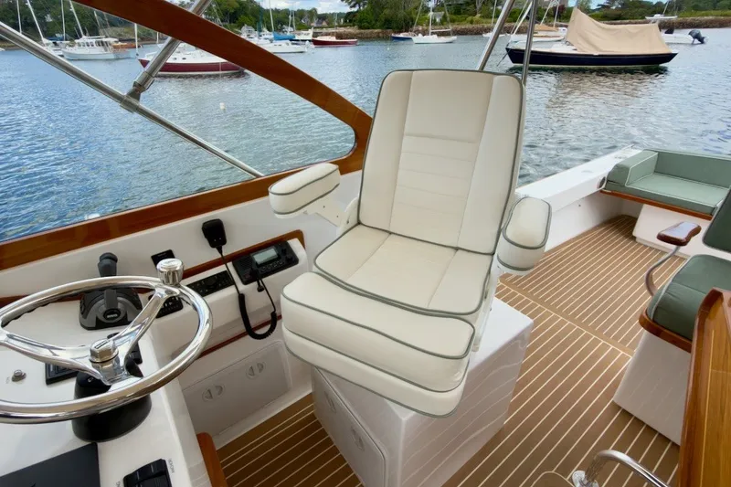 Slide: The Image of 2023 Fortier 33 boat interior with helm seat and steering wheel, docked on calm water. - 29