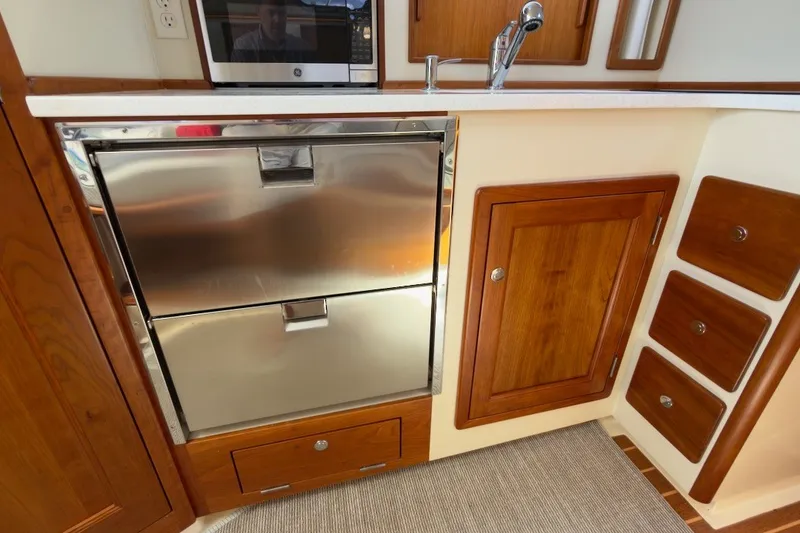 Slide: The Image of 2023 Fortier 33 yacht kitchen with stainless steel appliances and wooden cabinetry. - 54