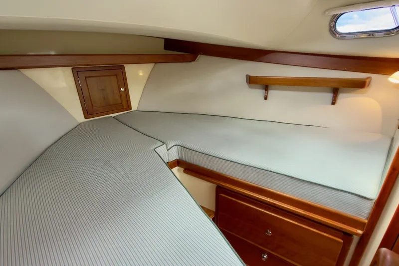 Slide: The Image of 2023 Fortier 33 cabin interior with cozy bed, wooden storage, and small window. - 45