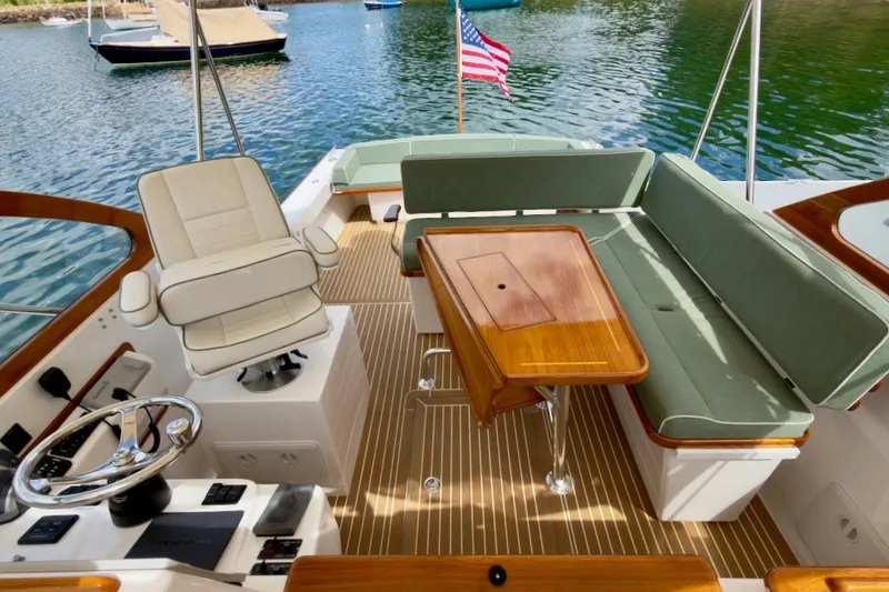 Slide: The Image of 2023 Fortier 33 boat interior with seating, table, and steering wheel on water. - 21
