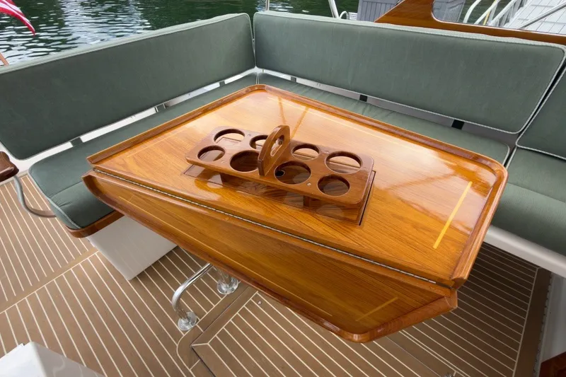 Slide: The Image of Luxurious wooden table on 2023 Fortier 33 boat with cup holder, green seating, and water view. - 25