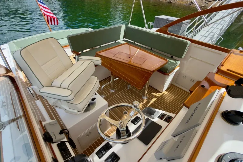 Slide: The Image of 2023 Fortier 33 boat interior with helm, seating, and wooden table on water. - 22