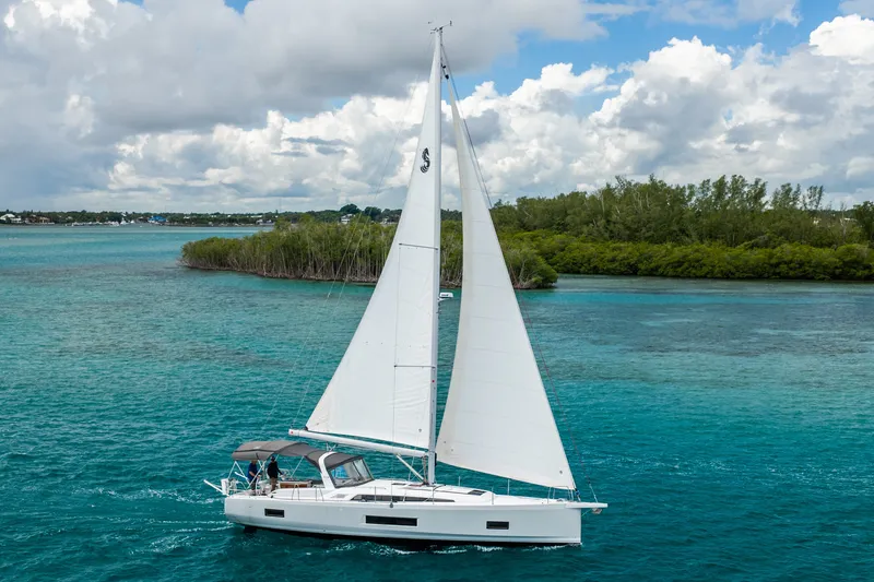 The Image of 2020 Beneteau Oceanis 46.1 sailing in clear turquoise waters under a cloudy sky. - 1