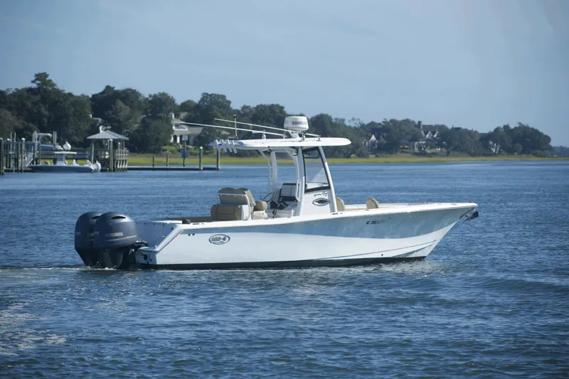 Slide: The Image of 2017 Sea Hunt Gamefish 27FS boat cruising on a calm lake with scenic background. - 2