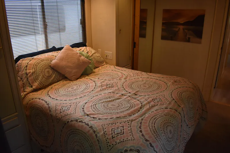 Slide: The Image of Cozy bedroom in a 1996 Stardust Cruisers houseboat with patterned bedding and wall art. - 17