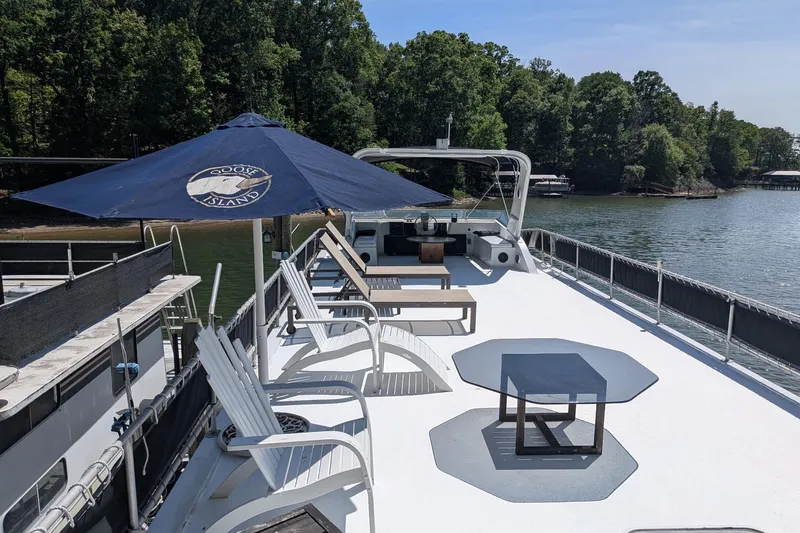 Slide: The Image of Rooftop deck of 1996 Stardust Cruisers houseboat with chairs and umbrella on a lake. - 37
