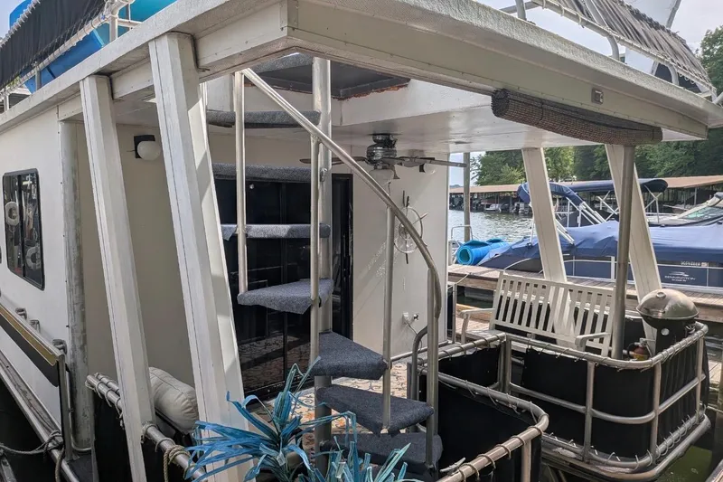 Slide: The Image of 1996 Stardust Cruisers houseboat with spiral staircase and outdoor seating at a marina. - 43