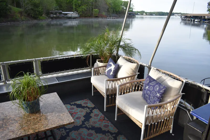 Slide: The Image of Houseboat deck with wicker chairs, decorative pillows, and plants overlooking a serene lake. - 42