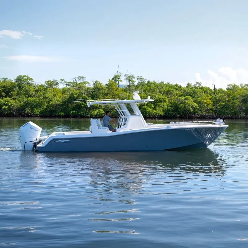 The Image of 2025 Invincible 33 Open Fisherman boat cruising on calm water near lush greenery. - 0